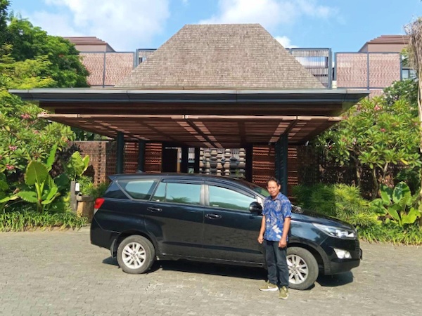 ヌサドゥアのホテルの車寄せに停まる黒いトヨタ イノーバと、バティックシャツのドライバー