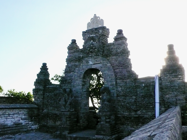 ウルワツ寺院の石造りの門と、夕方の光に照らされた寺院の塀