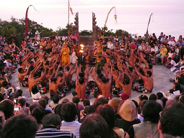 両手を高く上げて声を合わせるケチャの踊り手たちと、夕暮れの空