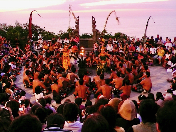 夕焼けの空の下、輪になった踊り手たちと舞台の中央で演じる役者